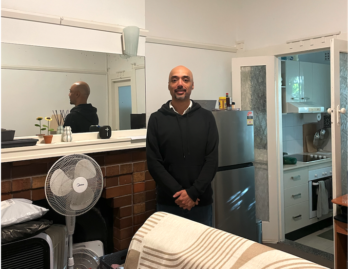Duncan in his room with the kitchen in the background